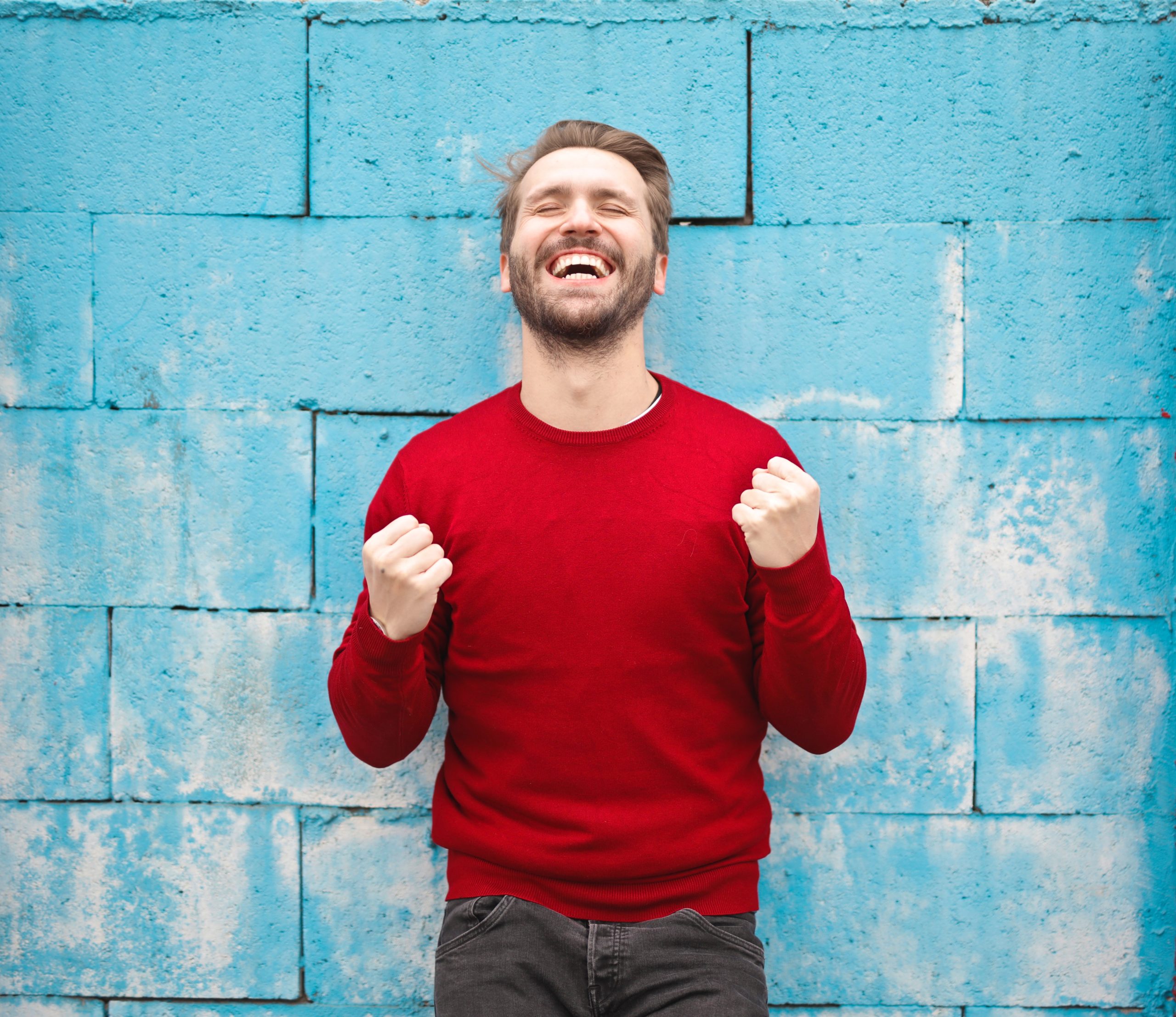 happy man in front of a blue painted wall