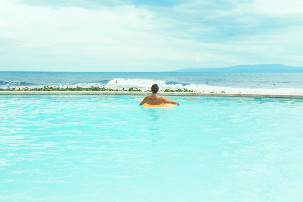 man on a floater on a pool near the beach